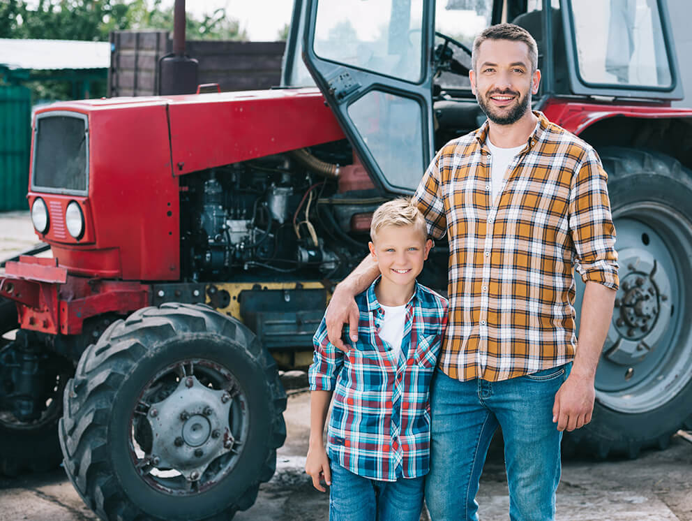 Father and son in front of tractor.